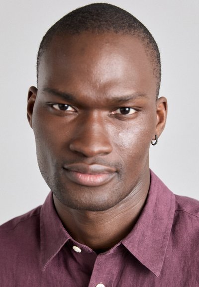 Portret al unei persoane cu piele închisă la culoare, păr scurt, purtând o cămașă din in de culoare purpurie închisă cu guler și un cercel mic din argint.