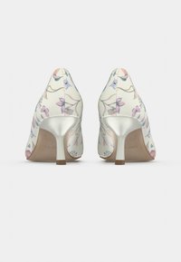 Chaussures à talons hauts en cuir crème avec motif floral, bout légèrement pointu et accent argenté brillant sur le talon.