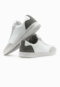 Weiße Leder-Sneaker mit grauen Wildlederakzenten. Sie verfügen über eine glatte Oberfläche, ein Schnürdesign und Perforationen an den Seiten zur Belüftung.
