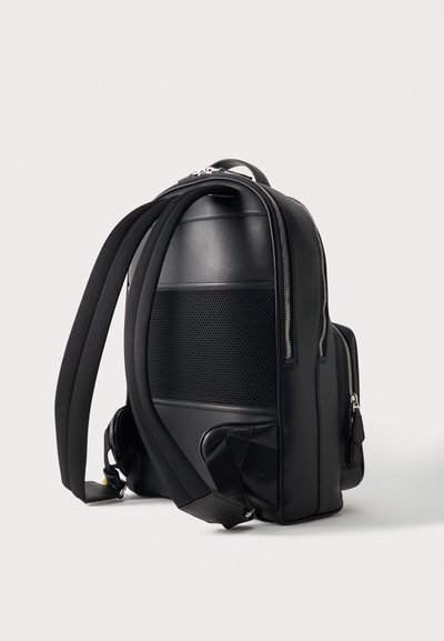 Sac à dos en cuir noir avec bretelles rembourrées, panneau arrière en mesh et fermetures éclair argentées visibles sur un fond clair uni.