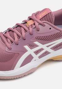 B baskets de sport roses avec une tige en maille texturée, des accents blancs et une semelle en caoutchouc. Lacets dans une teinte rose assortie avec une étiquette de logo en jaune.