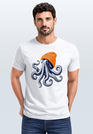 Man with short dark hair and beard wearing a white T-shirt with a blue octopus wearing an orange beanie graphic.
