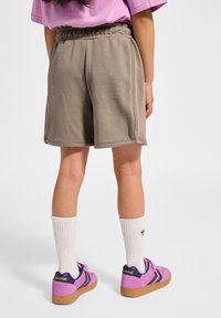 Kaki shorts med elastisk midja, med en avslappnad passform. I kombination med vita strumpor och rosa sneakers med lila detaljer.