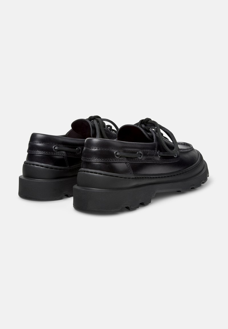Sorte lædersko med rund tå, tekstureret finish, tyk sort sål og kontrasterende snøre detaljer på siderne.