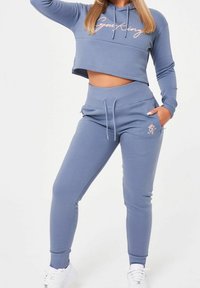 Ljusblå kortärmad hoodie med texten "Gym King" och matchande sweatpants. Tyget är mjukt med en slät textur, och har elastiska ärmslut och midja.