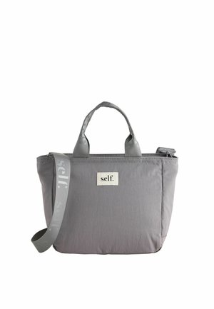 Gray tote bag with two short handles and an adjustable shoulder strap, featuring a white patch with the word "self." on the front.