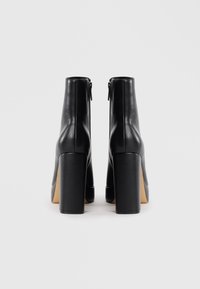 Black leather ankle boots with a high block heel, smooth texture, and a zipper closure on the back for easy wearing.