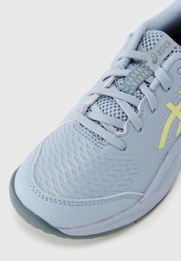 Αθλητικό παπούτσι ανοιχτού μπλε χρώματος με υφή στο πάνω μέρος, λεπτομέρειες από δίχτυ και ανακλαστικές επισημάνσεις. Διαθέτει ενισχυμένη μύτη και μαλακό πάτο.