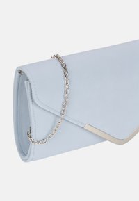 Pochette en cuir bleu clair avec une chaîne métallique et un rabat angulaire. Texture lisse avec des accents de design minimalistes.