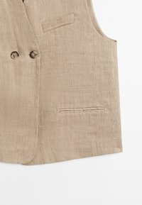 Beige kordflorsväst med dubbla knappar, en ficka och en texturerad yta, designad utan ärmar för en skräddarsydd passform.