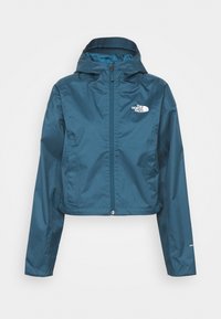Veste imperméable à capuche bleu sarcelle avec fermeture éclair frontale, logo The North Face sur la poitrine et étiquette Dryvent sur la manche.