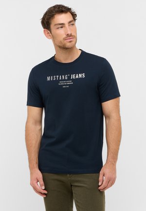 Granatowa koszulka bawełniana z okrągłym dekoltem, krótkim rękawem i białym nadrukiem z napisem "MUSTANG JEANS" z przodu.