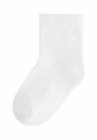Chaussette en coton blanc avec une texture côtelée, longueur mi-mollet, finition lisse et bout arrondi. Design simple, sans motifs ni accents supplémentaires.
