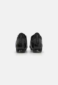 Botas de fútbol negras con una parte superior texturizada, logotipo en el talón y clavos moldeados para tracción. Diseño elegante y aerodinámico.