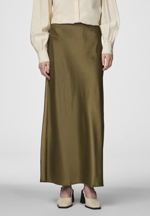 Maxi spódnica z oliwkowej satyny o gładkiej texture, prostym kroju i subtelnym połysku, zestawiona z kremowymi butami na kwadratowym obcasie.