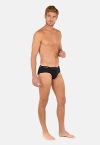 Schwarze Unterhosen aus einem weichen Stoff mit einem logoed Bund. Der Schnitt ist eng anliegend und sorgt für Komfort und Unterstützung.