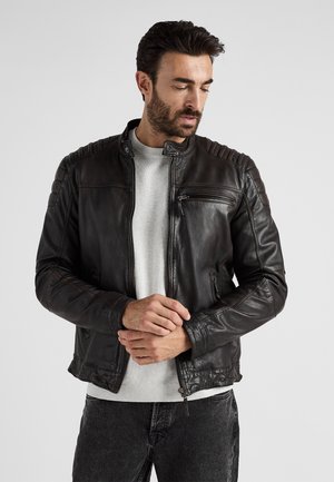 Zwarte leren motorjack met gestikte schouderaccenten, ritszak op de borst en opstaande kraag, gedragen over een grijze trui.