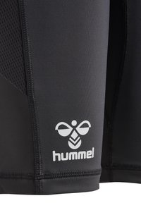 Svarta träningsshorts med mesh-sidopaneler, med en vit logotyp och texten "hummel" på nederdelen av benet. Slät struktur, figurnära design.