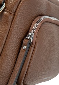 Borsa in pelle marrone con texture, dotata di una zip argentata e un tirante in pelle fissato da un rivetto in metallo.
