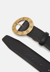 Zwarte leren riem met een ronde gouden gesp met reliëfletters en symbolen, waaronder "Fiorucci 1967", een zachte textuur en schone randen.