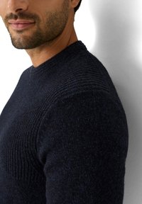 Granatowy dzianinowy sweter z prążkowanym teksturem na ramionach i dekolcie. Obcisły fason z okrągłym dekoltem i długimi rękawami, wykonany z miękkiego materiału.