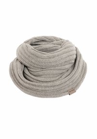 Gehaakte grijze sjaal met ribbelstructuur, opgerold ontwerp en een klein etikettje. De stof lijkt zacht en warm, geschikt voor koud weer.