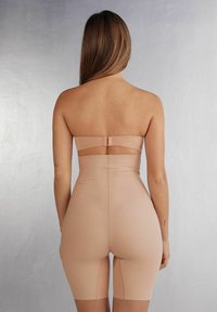 Naadloze huidkleurige lichaamshaper met een strapless ontwerp, mid-thigh lengte, gladde textuur en subtiele stiksels langs de naden.