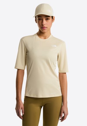 Camiseta deportiva beige claro de manga corta con tela texturizada y cuello redondo, combinada con pantalones verde oliva y una gorra a juego.