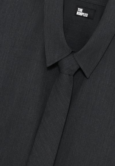 Dunkelgraues Hemd mit klassischem Kragen und passender Krawatte. Der Stoff wirkt glatt mit einer subtilen Textur. Etikett sichtbar im Kragen.