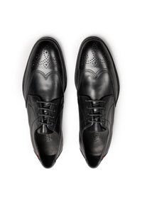 Chaussures habillées en cuir noir avec une finition lisse, dotées d'un design à bouts perforés et d'un système de laçage. Semelles durables, silhouette classique.