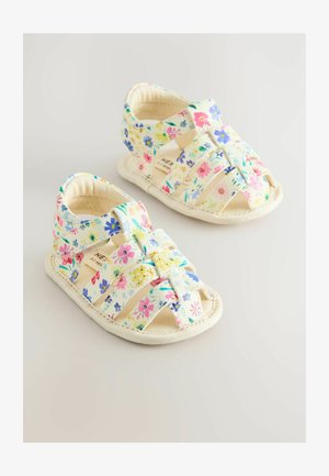 Blumenmuster-Toddler-Sandalen mit einem Obermaterial aus beigem Stoff und weißer Sohle. Mit überkreuzten Riemen und geschlossenem Fersenbereich für Unterstützung.