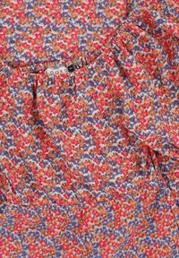 Patronenblouse van lichtgewicht stof, met een multikleurig ontwerp in oranje, roze en blauwe tinten; geplooide halslijn en zachte textuur.