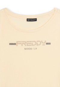 Camiseta color crema con cuello redondo, "FREDDY" en un diseño de puntos y el texto "MOOD UP" impreso debajo en el pecho.