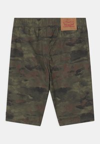 Shorts cargo en imprimé camouflage dans des tons de vert et de marron, fabriqués en tissu avec un léger éclat. Dotés d'une taille élastique et d'une étiquette en cuir à l'arrière.