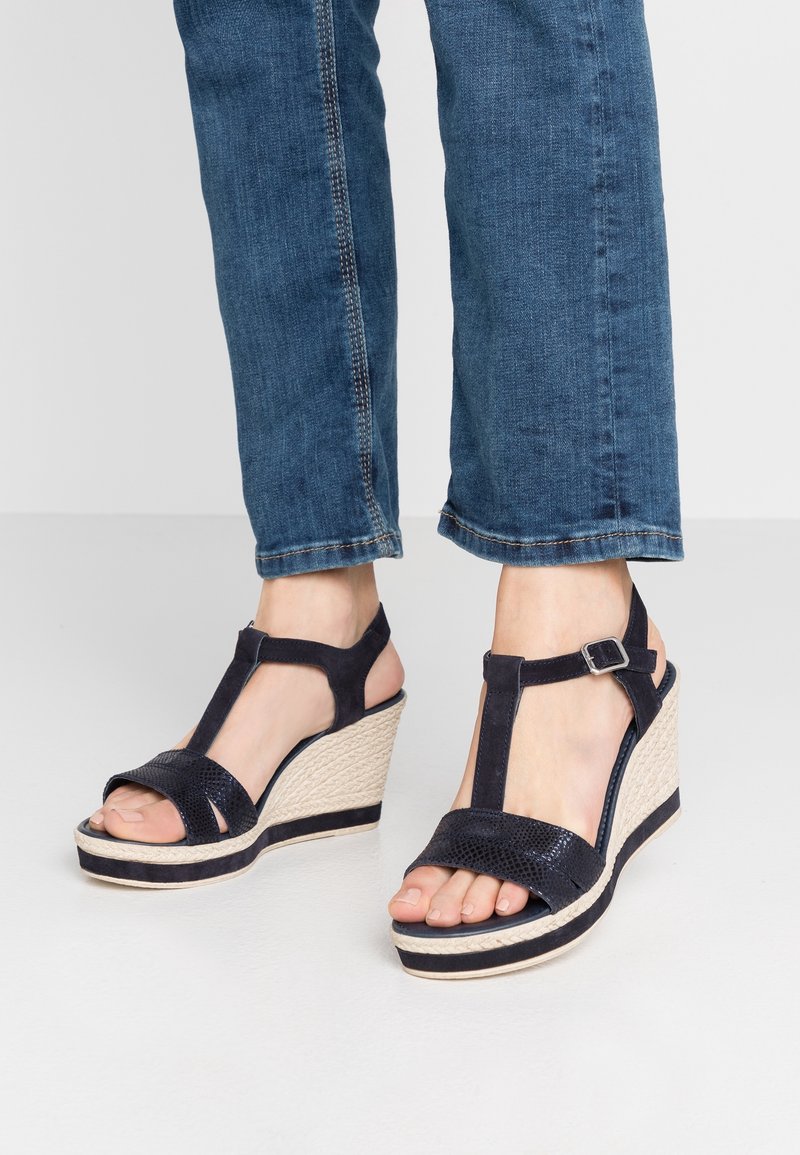 Sandales compensées bleu marine avec plateforme en jute tissé, design à bout ouvert et bride ajustable à la cheville. Accents en tissu texturé sur les brides.