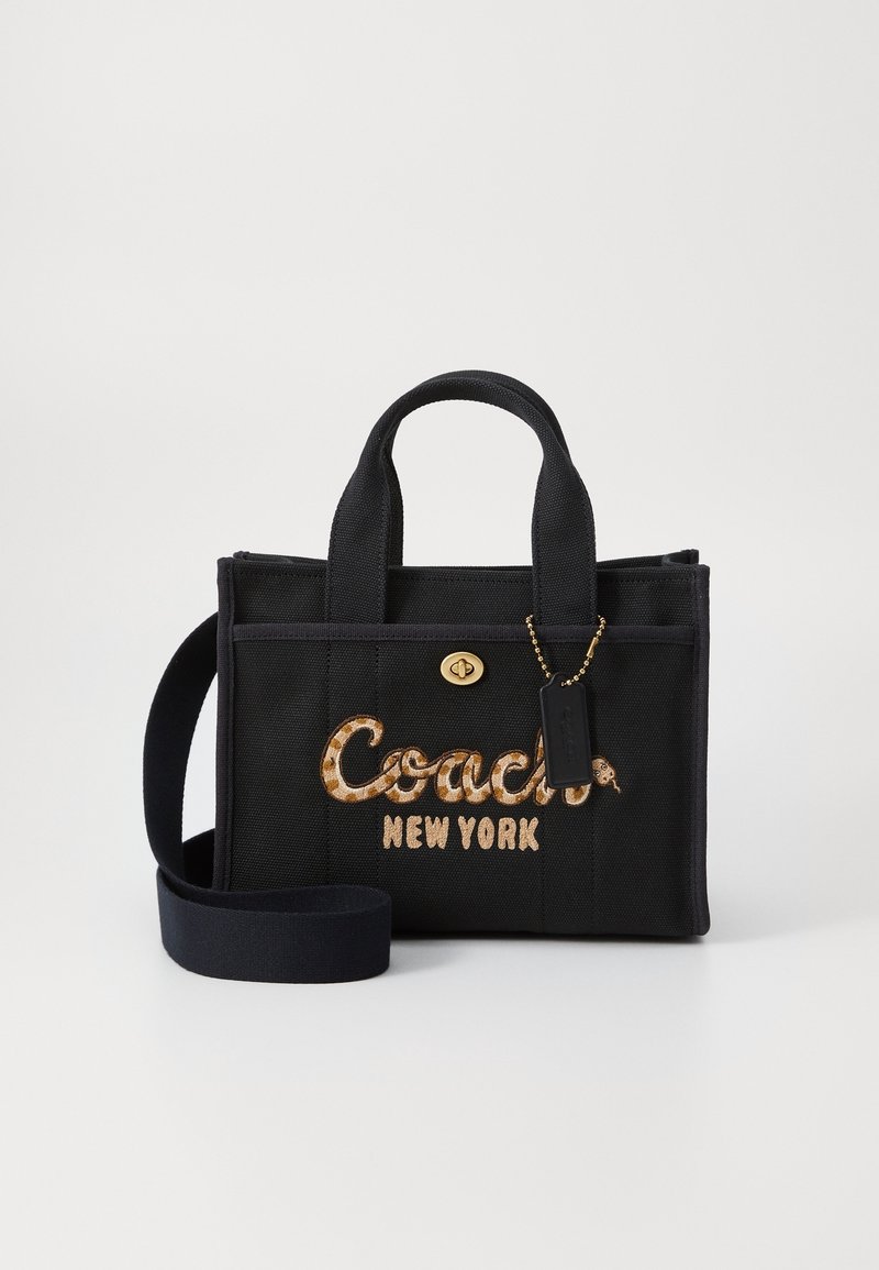 Sac à main en tissu noir avec poignées courtes, bandoulière, fermoir doré et logo « Coach New York » brodé dans un motif léopard.
