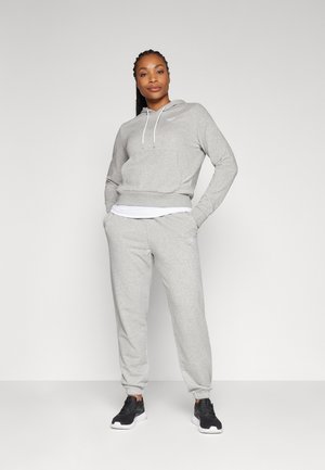 Grå hettegenser med justerbare snorer, en frontlomme og matchende tettsittende joggebukser, parret med sorte joggesko.