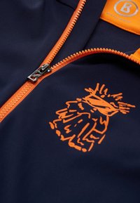 Mørkeblå lynlåsjakke med orange lynlås og detaljer. Har et legende orange grafisk design på fronten og en glat tekstur.
