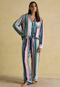 Multicolored striped pajama set featuring long sleeves and matching pants, made of a smooth fabric with a drawstring waist and pocket detail.