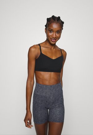 Sutiã desportivo preto com alças largas, combinado com calções cinzentos de cintura alta com padrão, apresentando uma textura suave e um design ajustado.