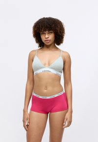 Šedý bavlněný bralet s bílým páskem Calvin Klein, doplněný růžovými bavlněnými šortkami se stejným páskem. Hladká textura, jednoduchý design.