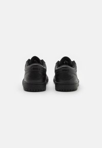 Sorte lær sneakers med en glat overflade, rund form og tekstureret gummisål. Har logo detaljer på hælen og polstret krave.
