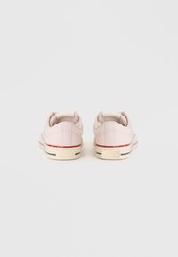 Sneakers in tela rosa chiaro con suole in gomma bianca e accenti rossi e blu. Presentano una punta rotonda e il logo distintivo sul tallone.