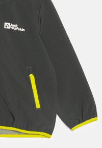Giacca nera realizzata in materiale morbido, con una tasca con zip gialla, dettagli gialli sui polsini e sull'orlo, e un logo sul petto.