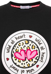 Schwarzer Sweatshirt mit einem runden Grafikdesign, das ein Leopardenmuster, zwei pinke Herzen und den Text "wild at heart" in einem kreisförmigen Layout zeigt.