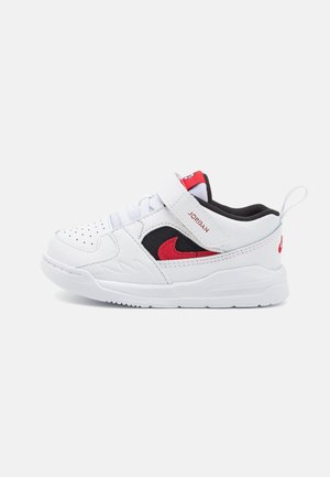 Zapatilla blanca para niño pequeño con el logo Nike en rojo y negro, cierre de velcro, cordones en la parte delantera y lengüeta para tirar en fondo blanco.