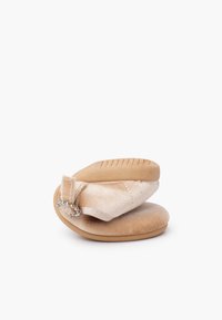 Scarpa per bambino di colore beige morbido con suola in gomma flessibile piegata a metà, dotata di una cinghia con fibbia decorativa in strass.