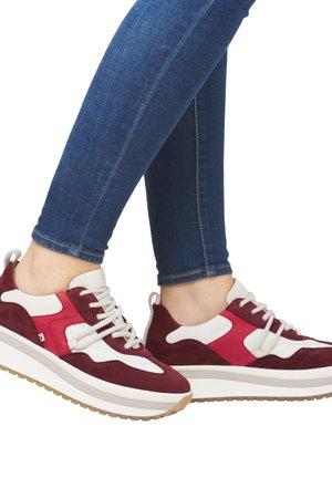 Baskets rouges et blanches en daim et en matériaux synthétiques, avec une semelle épaisse et un design décontracté, dotées d'un système de fermeture à lacets.