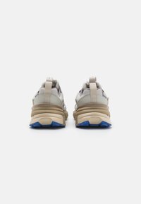 Beige and gray sneakers with blue accents, featuring a chunky sole and a textured design. Includes rear pull tabs for easy wear.