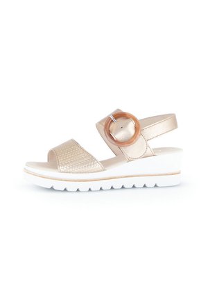 Sandals with a woven metallic gold upper, wide strap, a circular wooden accent, and a white wedge sole with a textured surface.